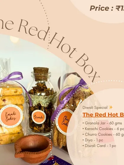 A graphic detailing the contents of 'The Red Hot Box' hamper. It includes a granola jar, Karachi cookies, and churro cookies, making it a perfect snack-filled gift.