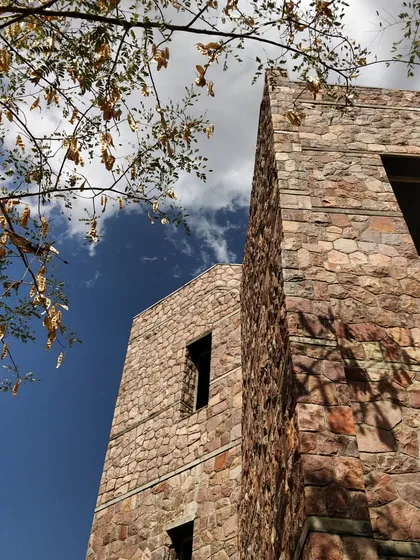 The stone-clad facade of the IIHMR Jaipur campus. The building was designed with an evaporative cooling system, and a causeway on the site acts as a dam to impound rainwater, helping to recharge the local water table.