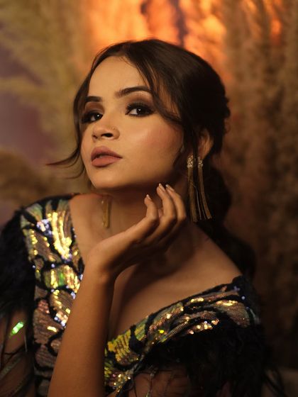 A graceful pose with a hand delicately placed by her chin. This portrait highlights the model's elegant features and the glamorous makeup.