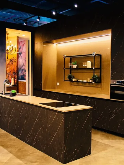 Another view of our showroom, showcasing a large island kitchen with dramatic lighting and bold finishes.