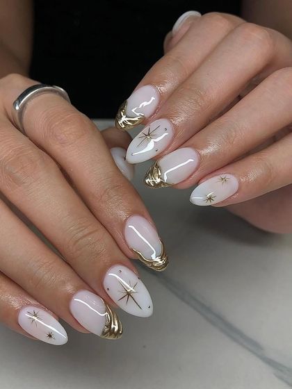 Celestial and chic. These milky white almond nails are adorned with 3D gold chrome and delicate gold star decals.