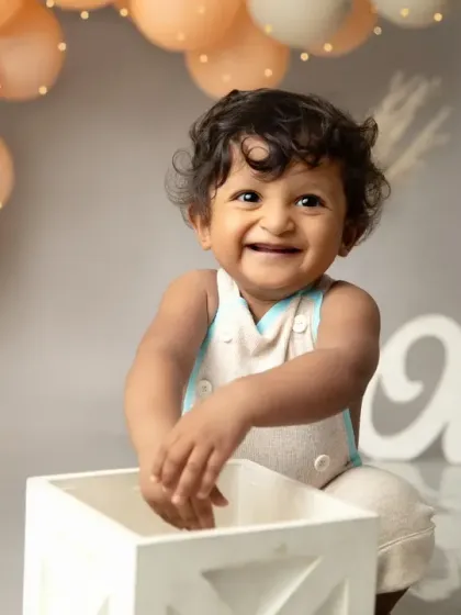 A huge, gummy grin of pure happiness. This rustic-themed cakesmash with neutral balloons and a simple wooden box is perfect for a stylish little boy's first birthday.