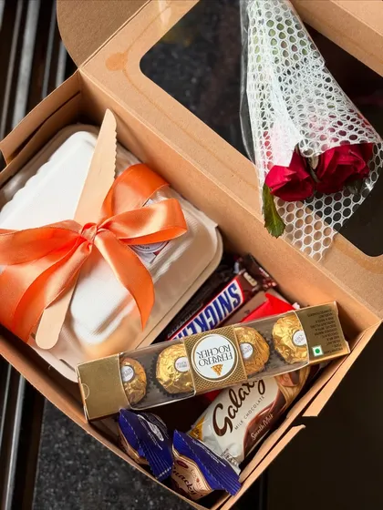 For the ultimate sweet tooth, this mini gift box is packed with treats. It features a bento cake, a small bouquet of roses, and a selection of popular chocolates like Ferrero Rocher, Galaxy, and Snickers.