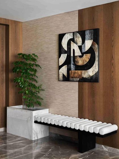The entrance foyer of the 'RYSA' apartment features a modern upholstered bench and abstract art, set against a backdrop of warm wood paneling.