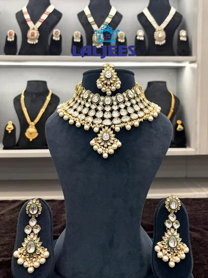 A classic, grand bridal choker set that never goes out of style. This piece features large uncut polki-style stones, layered with smaller stones and pearl drops, complete with matching earrings and maang tikka.