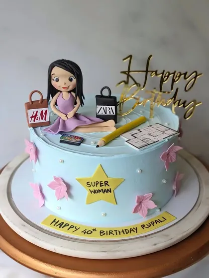 A cake for a superwoman architect celebrating her 40th. The design includes her blueprint, a pencil, and shopping bags from her favorite brands.