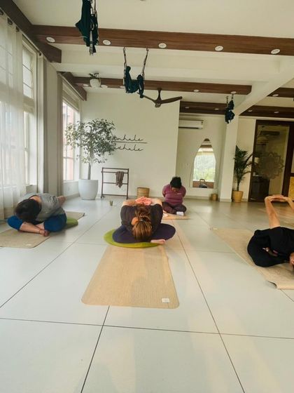 A class practices a seated forward fold, a calming and grounding posture.