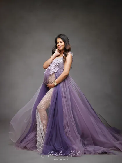 A vision in lavender. This flowing gown with floral appliqué and a sheer lace legging offers a unique blend of romance and modern style, perfect for a memorable maternity portrait.