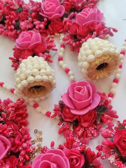 A close-up of a vibrant pink floral jewellery set, showing the detailed craftsmanship of the flower earrings and other pieces.