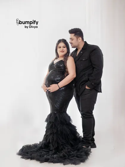 A sleek and glamorous couple's portrait. The mom-to-be shines in a black sequined mermaid gown, a perfect choice for a sophisticated and modern maternity shoot.