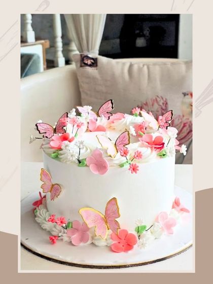 A beautiful and delicate cake adorned with pink and white flowers and fluttering wafer paper butterflies.