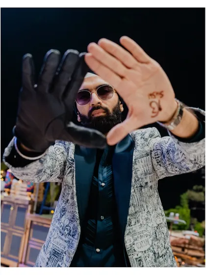 A creative portrait of the groom, framing his face with his hands, one of which shows his bride's name in henna.