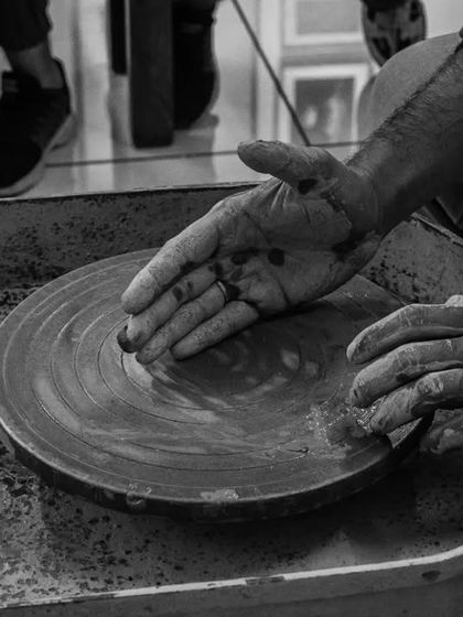 A black and white photo capturing the moment of centering clay on the wheel. This is where the connection between the artist and the material begins.