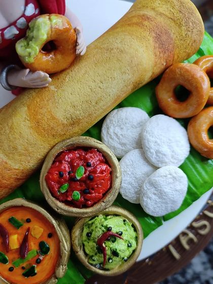 A detailed shot of the edible South Indian platter, showcasing the texture of the dosa, the fluffy idlis, and the vibrant colors of the chutneys and sambar.