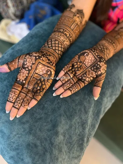 A stunning bridal design combining popular motifs. The palms feature peacocks, while the arms are decorated with palace architecture, creating a truly grand look.