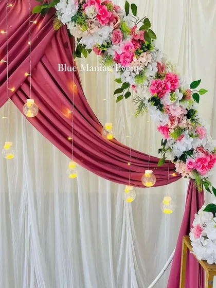 A close-up of the wine-colored Roka backdrop, showing the delicate hanging glass globes and the texture of the floral arrangements.