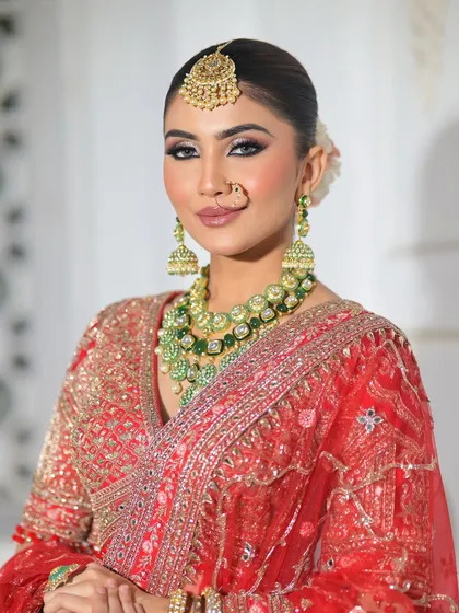 This shot captures the bride's confident gaze. The makeup enhances her features beautifully, with a focus on defined eyes and glowing skin that looks stunning against the red lehenga.