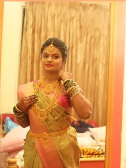 A mirror selfie capturing the final reception look. The bride is glowing in her silk saree, with makeup that emphasizes a flawless base and complements her traditional gold jewelry.