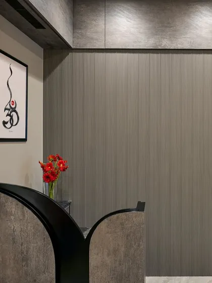 The reception area features a textured grey wall and a custom-designed desk. A piece of calligraphy art adds a spiritual and personal touch, making a great first impression.