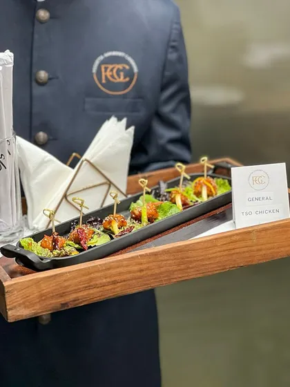 A server presents a tray of General Tso Chicken bites. This dish is a crowd-pleaser, offering a perfect balance of sweet and spicy flavors, ideal for a cocktail party or pre-dinner appetizer.
