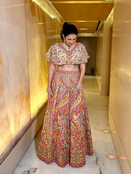 A vibrant and colorful lehenga by Abu Jani Sandeep Khosla. The cape-style blouse with flutter sleeves adds a playful and modern touch to the traditional paisley skirt.