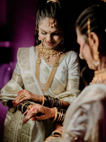 The bride admires her hands, beautifully decorated with mehndi and bangles. This is a lovely, quiet moment that captures the traditional details of her bridal attire.