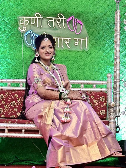 Seated on the traditional swing, this mom-to-be is the picture of happiness. Her full look, including the expertly draped saree and glowing makeup, is designed for comfort and elegance during her Dohale Jevan.