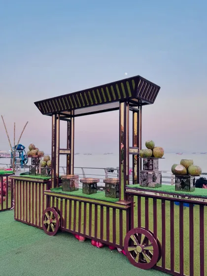 A rustic cart-style counter serving fresh coconut water, set against a beautiful sea view.