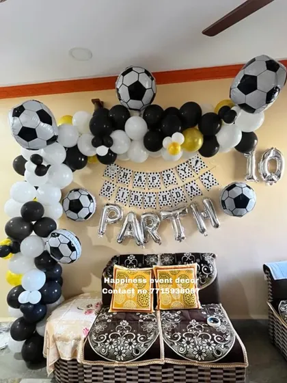 A football-themed birthday decoration for a 10th birthday. The setup includes a black and white balloon garland and multiple football-shaped foil balloons, perfect for a sports fan.