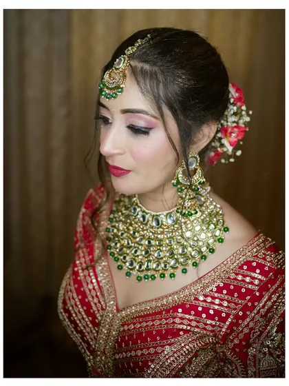 A classic three-quarter profile of the Punjabi bride. This angle beautifully showcases her hair, makeup, and the intricate details of her earrings and lehenga.