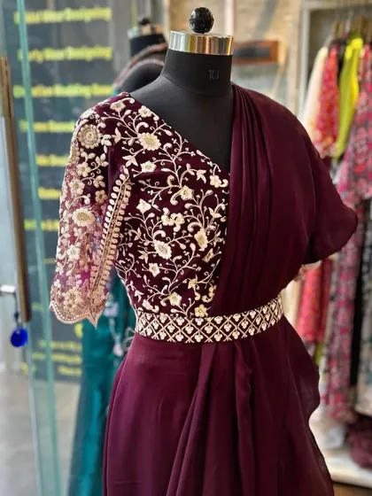 For a modern and chic look, I design ready-to-wear outfits like this designer ruffle saree in a deep wine color. It's paired with a stunningly embroidered blouse and a matching belt, offering an effortless yet glamorous option for a cocktail or reception event.