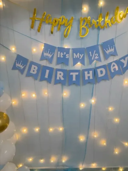 For smaller, more intimate celebrations, I can create a simple yet beautiful backdrop like this one. It features a blue curtain with fairy lights and a "It's My 1/2 Birthday" banner.