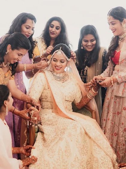 A heartwarming moment as the bridesmaids surround the bride, helping her get ready. Their smiles and care create a beautiful picture of friendship and support on the wedding day.