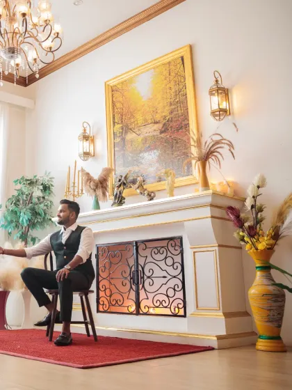 A creative portrait of the groom sitting by an elegant fireplace, reaching out towards the bride. This shot tells a story and highlights the beautifully styled set.