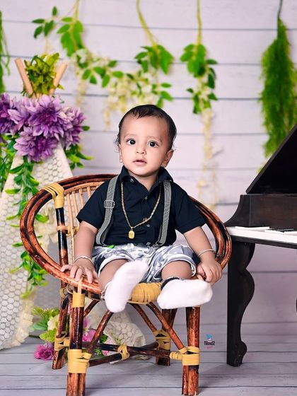 A toddler looking very dapper for his birthday photos, sitting by the piano.