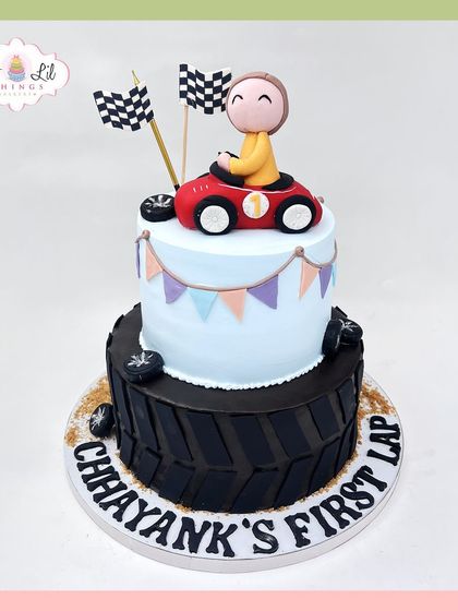 Chhayank's first lap! A cute race car-themed cake for a first birthday, with a checkered flag pattern and a little red car on top.