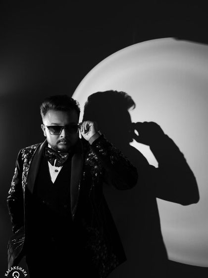 A moody black and white portrait of the groom, adjusting his sunglasses.