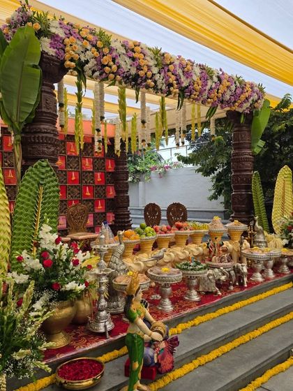 An angled shot of the outdoor mandapam, showing the intricate details of the pillars and floral arrangements.
