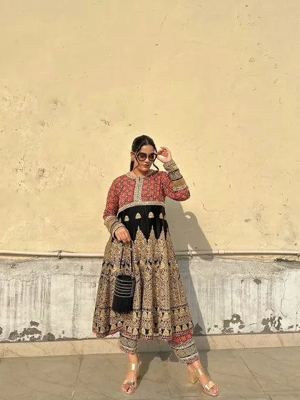 A confident pose showing the full ensemble. The black potli adds a touch of modern minimalism to the opulent, traditional dress.