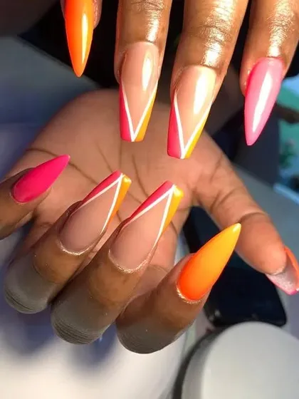 A dramatic set of long, stiletto nails with a neon orange and pink geometric French tip design.