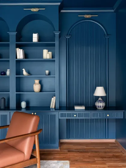 We believe in the power of color to transform a space. This library, drenched in a bold indigo blue, becomes a sophisticated and eye-catching retreat. The custom arched bookshelves and rich wooden flooring make this a dream space for any book lover.