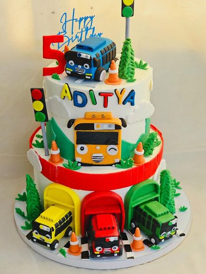 A full view of the two-tier Tayo the Little Bus cake. The design allows for plenty of space to feature all the colorful buses and road elements for an immersive theme.