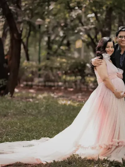 An enchanting portrait of an expecting couple enjoying a quiet moment together outdoors. The long train of the gown spreads out on the grass, adding a touch of romance to the scene.
