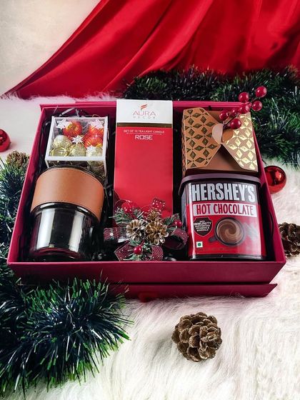 The vibrant red "Holiday Cheer" box filled with Hershey's hot chocolate, a scented candle, and other festive goodies.