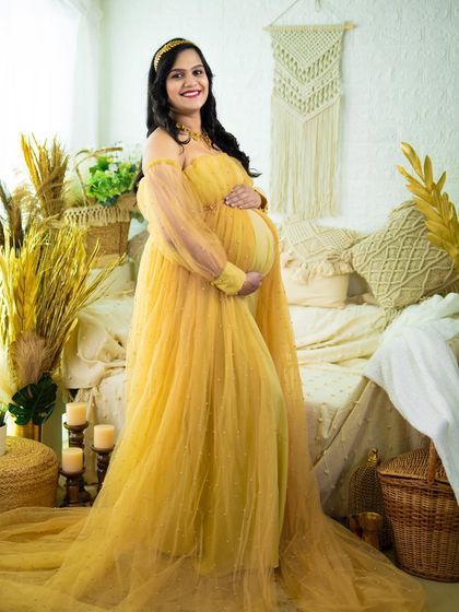 A full-length portrait of a mom-to-be in a flowing yellow gown. The bright color and airy fabric create a cheerful and beautiful image in our studio.