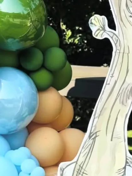 A detail of the vibrant balloon work and a tree cutout, adding to the Hundred Acre Wood atmosphere.