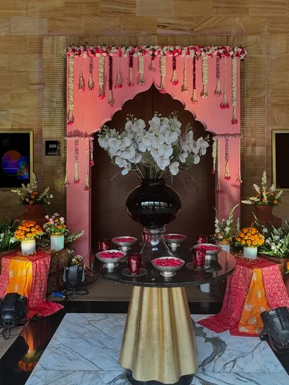 The entrance decor for the 'Bhaat & Tilak' ceremony, featuring a traditional arch, marigold garlands, and brass elements.