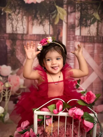 A playful moment captured as the little girl sticks her tongue out during her floral-themed photoshoot.