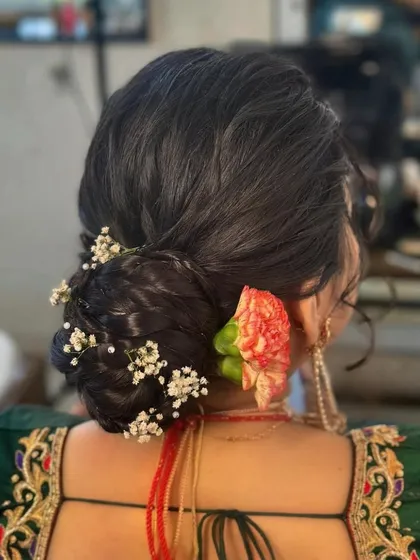 A close-up of the intricate floral bun hairstyle. We used a mix of baby's breath and a single carnation to create a delicate and beautiful hair accessory.
