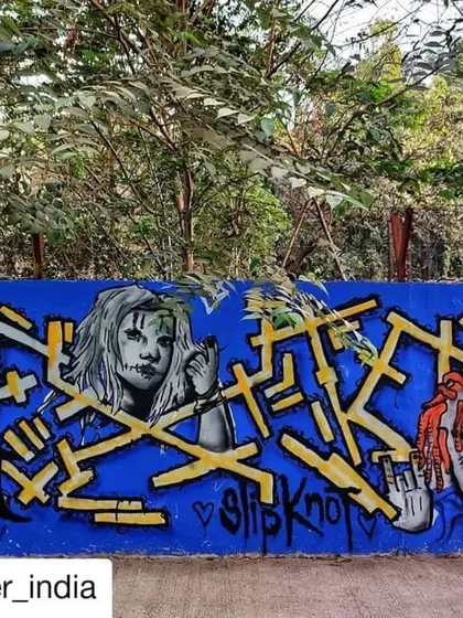 A tribute to the metal band Slipknot, featuring their iconic masks alongside complex yellow lettering on a bright blue wall. A great example of subculture representation in street art.